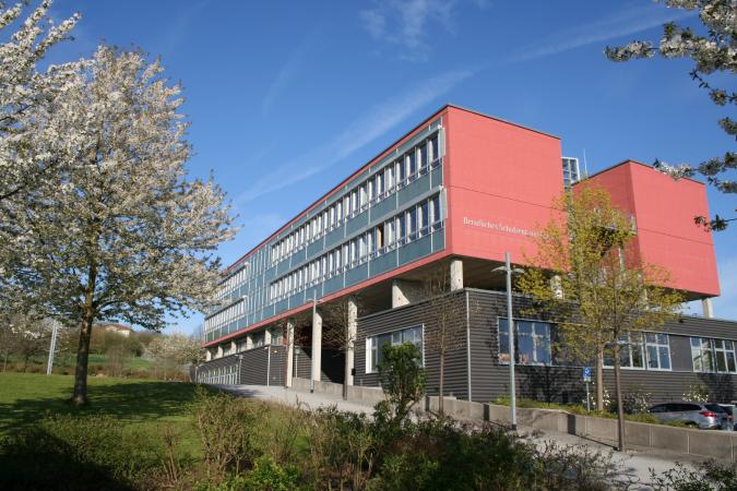 Blick auf das Schulgebäude mit blühenden Bäumen im Frühling