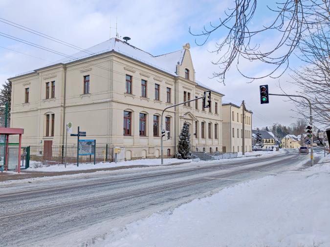 Blick auf das verschneite Schulgebäude von der Straße aus.