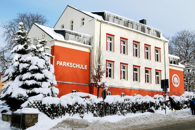 Blick auf das verschneite Schulgebäude von der Straße aus.